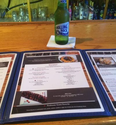 A bottle of beer and a menu are placed on a table, creating a casual dining atmosphere.