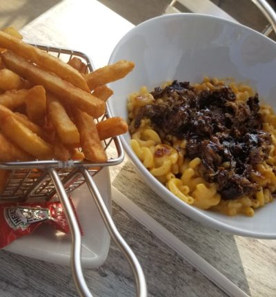 A bowl of creamy macaroni and cheese alongside a serving of crispy french fries.