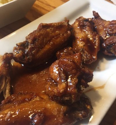 A plate of chicken wings served with gravy and a side of creamy mashed potatoes.